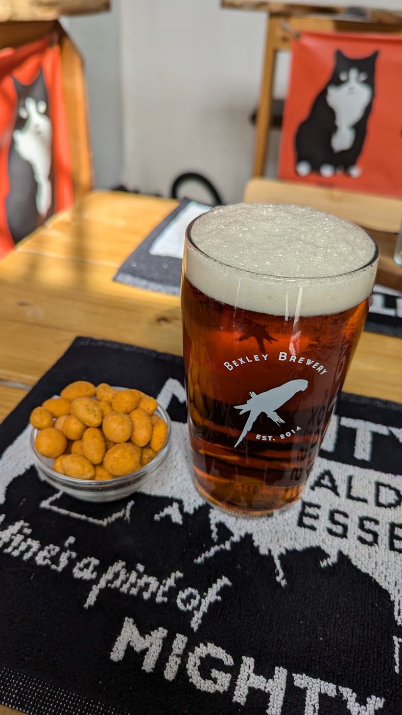 A pint of amber ale with a bowl of snacks