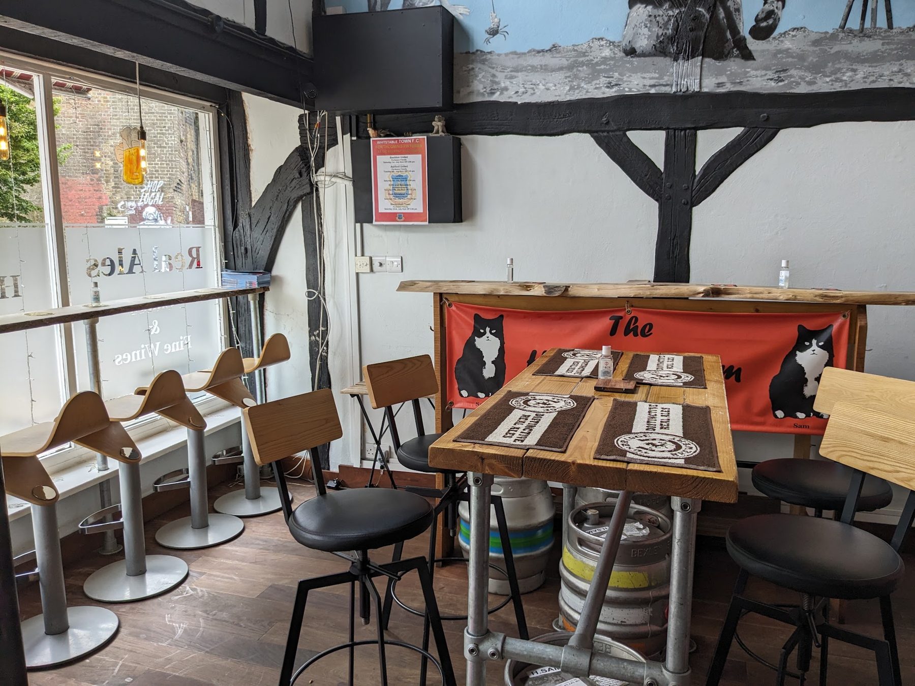 High tables and stools inside the micropub, with casks under the tables